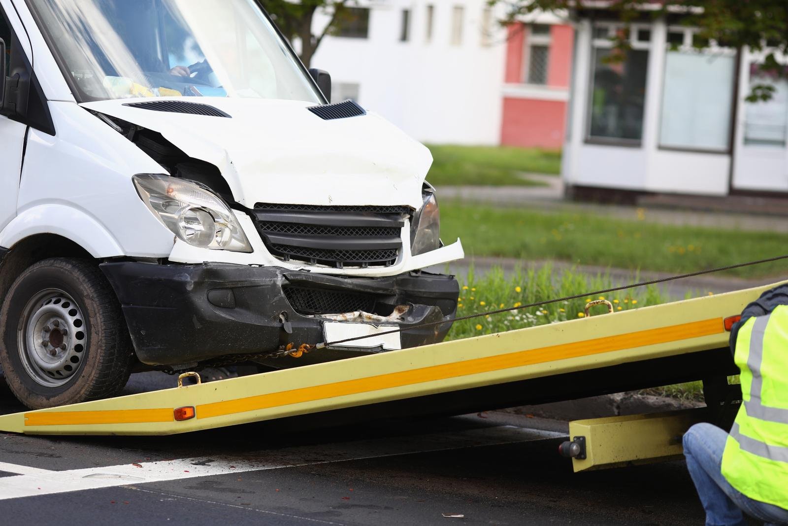 Damaged van being loaded onto a flatbed tow truck