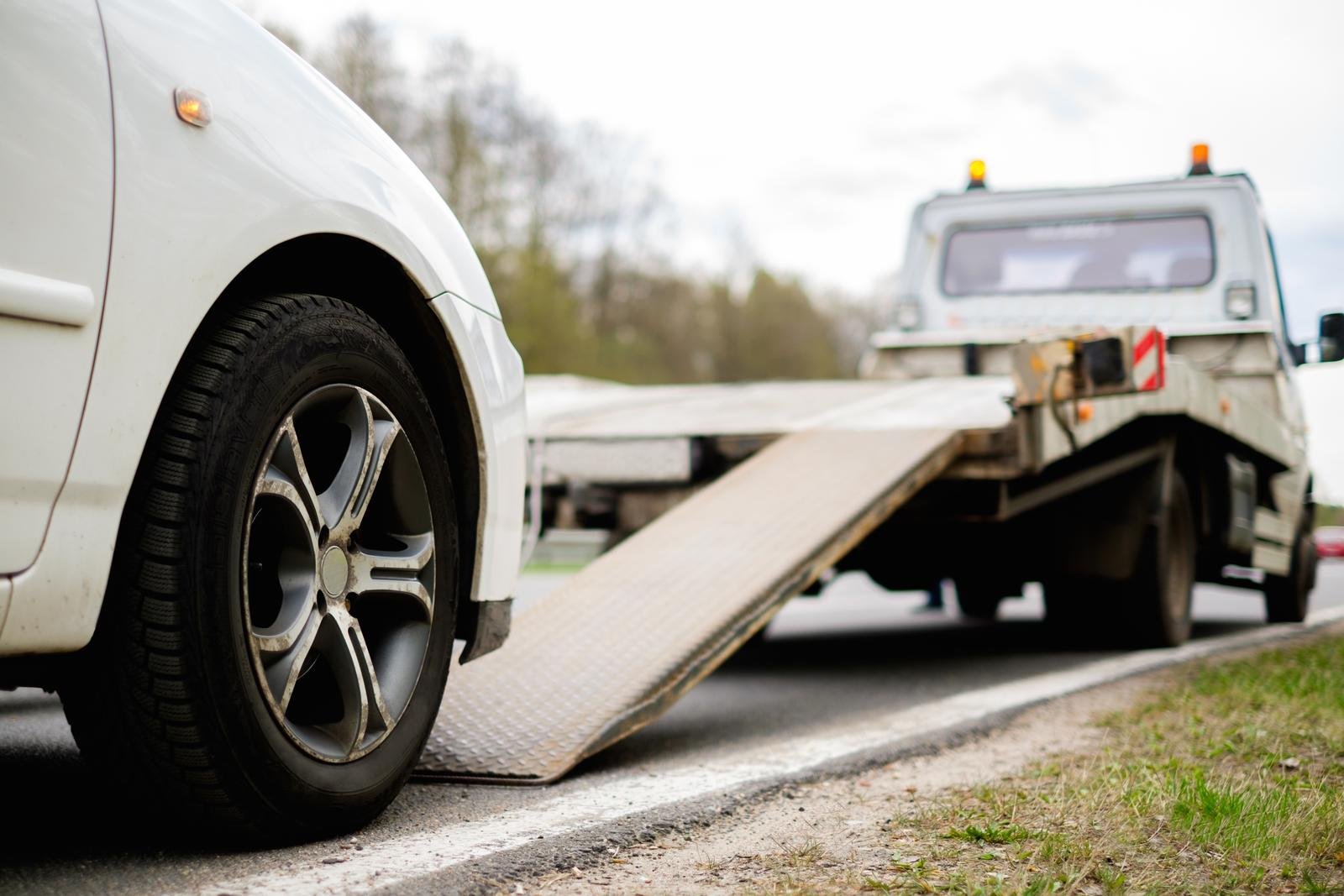 Car being loaded onto a flatbed tow truck on the roadside