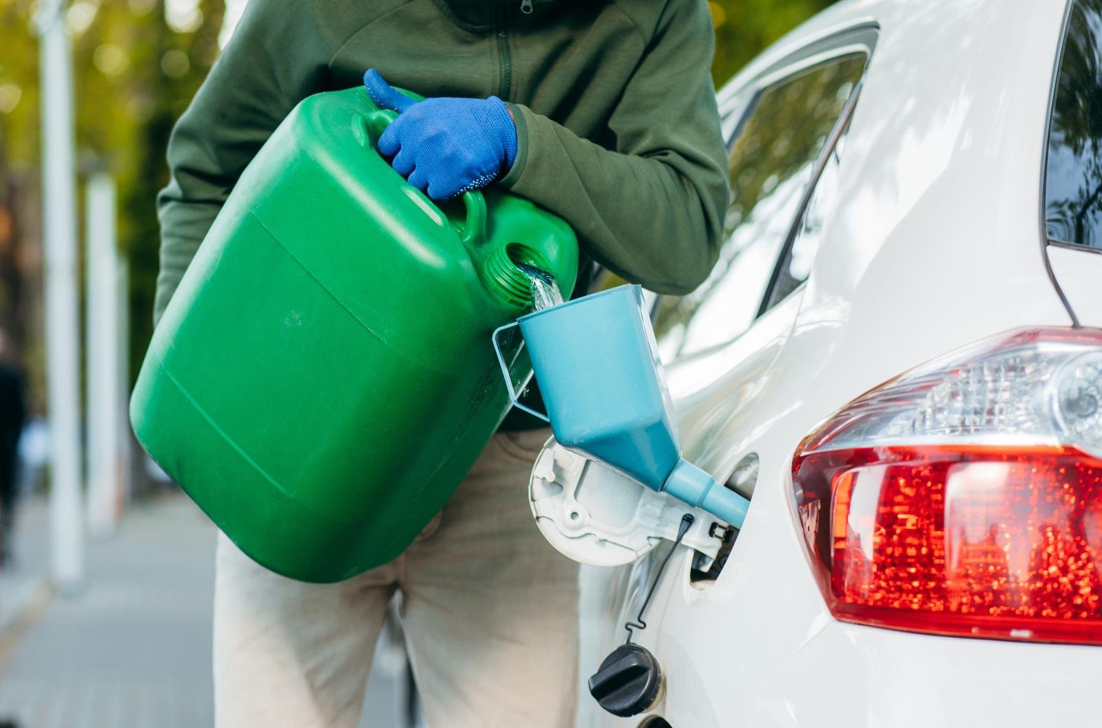 Person pouring fuel from a jerry can into a car