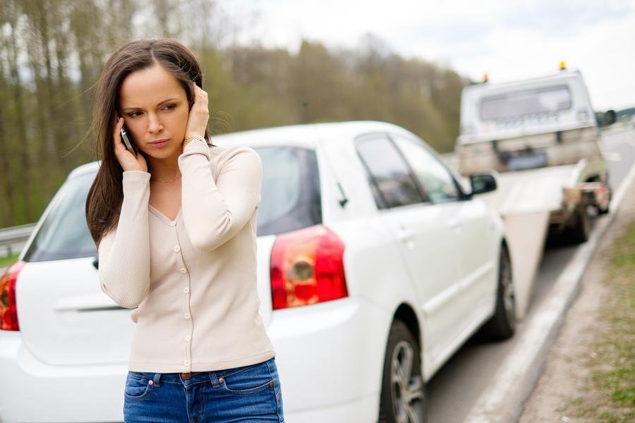 Driver on the phone beside her broken-down car