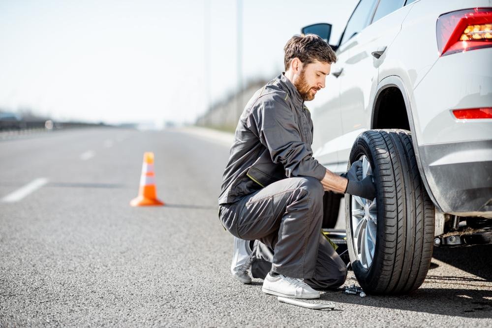 Tow operator changing a car tire on the roadside